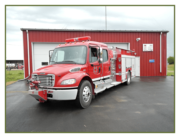 A fire truck in front a red garage.