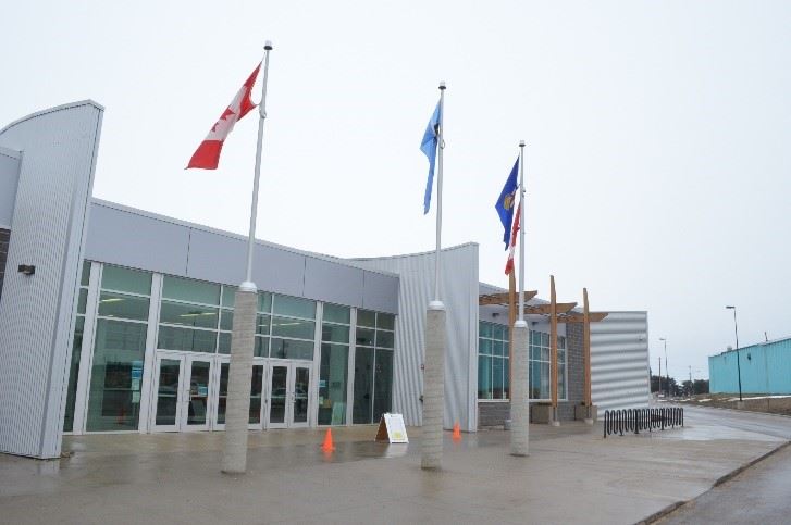 The modern facade of the Multi Recreation Centre, with flags waving above.